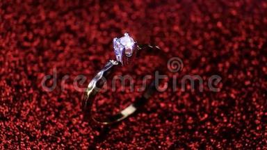 美丽闪亮的金色订婚戒指与大宝石钻石在闪光的红色背景。 情人节`礼物。
