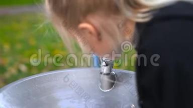 可爱的白种人可爱的金发女孩从水龙头里喝水，在附近的城市公园里有<strong>饮水机</strong>