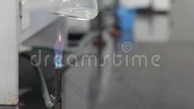在化学实验室用蓝色燃烧器火焰加热锥形烧瓶中的<strong>无色</strong>液体