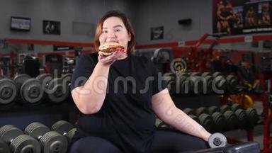 意志力和<strong>减肥</strong>理念.. 肥胖的漂亮女人在<strong>健身</strong>房锻炼时休息吃零食。 女孩