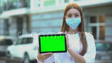 戴防护面罩的少女手持绿屏平板电脑，预防流感小贴士