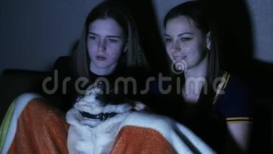 女孩们晚上在黑暗的房间里和狗狗一起看<strong>电视节目</strong>