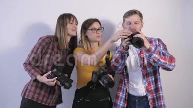 年轻的专业人士手中拿着数码相机，讨论在摄影记者研讨会上拍摄的照片