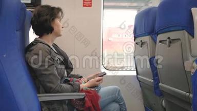 乘火车靠窗白种人女人拿着智能手机看窗外