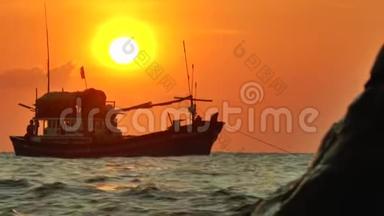 抛锚的渔船在夕阳的光<strong>线下</strong>在波浪中摆动的剪影