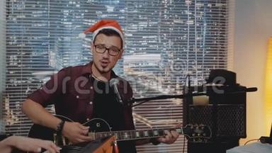 戴着圣诞帽的才华横溢的年轻人在家庭录音室录制他的新曲目