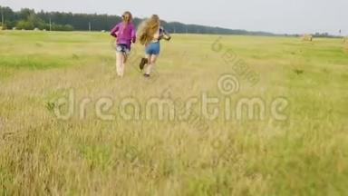 两个十几岁的女孩在干草堆背景下奔跑在乡间田野上。 可爱的女孩在乡间奔跑
