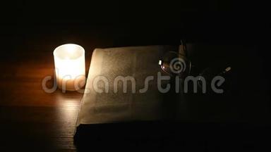 一支孤独的蜡烛在夜晚的桌子上闪烁，在一本开放的书面前。