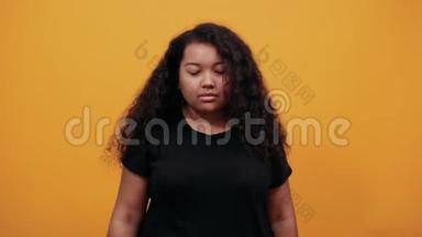 严肃的美国黑人妇女在橙色的墙上对着镜头露出<strong>三根手指</strong>