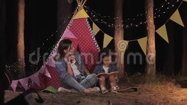 亲子关系，有爱心的妈妈和美丽的女孩子一起在野餐时一起读有趣的书