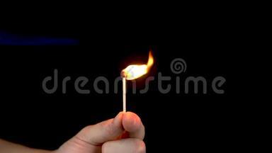 一个人从火中点燃火柴。 一个男人手里拿着一根火柴，在黑色背景特写上点燃。 慢慢