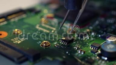 镊子从纸板上取出焊接芯片。 修理工更换芯片上的元件.. 更换无线电