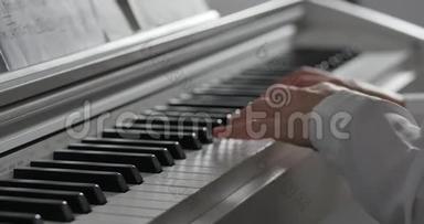 一名学生或专业钢琴家在一架漂亮的白色钢琴上演奏<strong>古典音乐</strong>，钢琴家的手