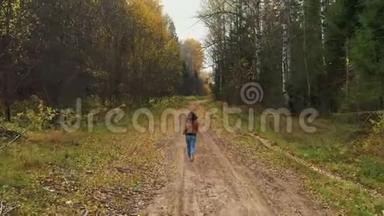 白种人女人在秋林路上<strong>奔跑的</strong>镜头。 <strong>阳光下</strong>黄色、橙色和绿色森林<strong>的</strong>叶子颜色