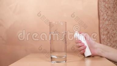 女孩的手随便地把两个放进一杯水里，放在桌子上。