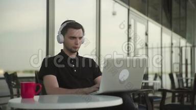 清晨，一个迷人的男人在咖啡馆里，通过平板电脑在线交谈，喝着咖啡
