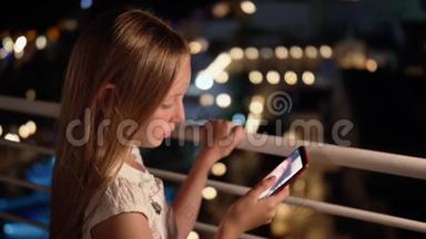 年轻<strong>女孩</strong>在黑暗阳台上的<strong>社交网络</strong>中看智能手机在线广播。 使用手机的少女