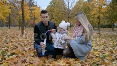 幸福的家庭观念，<strong>爸爸妈妈</strong>和小女儿在秋天公园玩肥皂泡