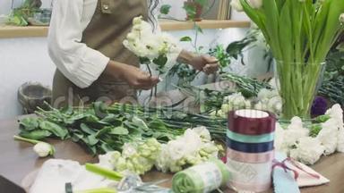 年轻迷人的女花店商人在他的花店里做一束花出售。 人民