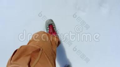 穿着橙色裤子和蓝色靴子的男人在雪地上行走