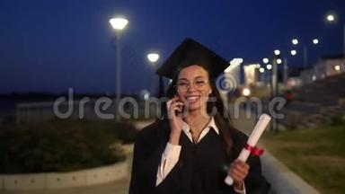 穿着黑色毕业礼服的年轻学生在电话里<strong>走来走</strong>去。