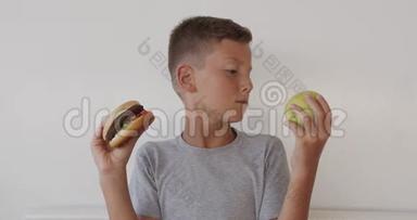 男孩选择健康或不健康的食物。 男孩在苹果和汉堡之间做出选择，健康还是快速，垃圾食品，选择了