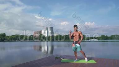 健美运动员在湖边的摄像机上展示他肌肉发达的身体