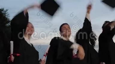 快乐而兴奋的混合种族的学生朋友在毕业典礼上，边走边扔帽子。