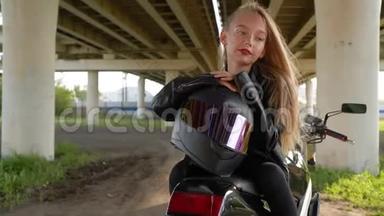 骑摩托车坐在城市桥下戴着摩托头盔的<strong>比基尼</strong>女孩。 穿<strong>黑色</strong>皮夹克的摩托女孩