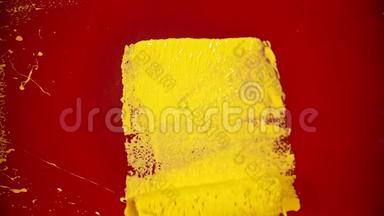 一个人用滚筒重新涂上黄色油漆的<strong>红墙</strong>