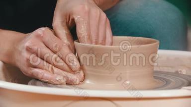陶器-主人正举起陶碗的墙壁，双手放在创意车间的陶工`轮子上