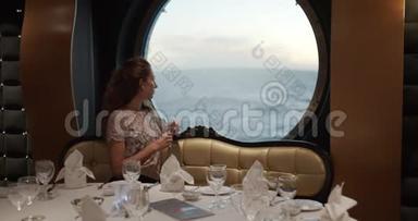女观看日落从窗口豪华游轮与一杯葡萄酒在休息。