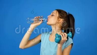 深色长发的黑发女孩在她身后喝着塑料透明瓶子里的纯净水