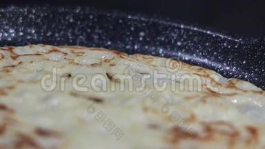 厨师正在黑锅里煎一个金<strong>黄可</strong>口的薄煎饼，锅里煮着，蒸着植物油