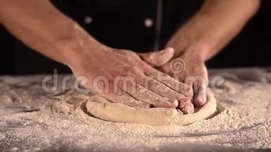 男人的手在面粉里揉比萨饼面团。 擀面团的特写