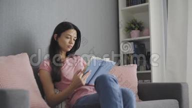 美丽的年轻<strong>女子坐在沙发上</strong>看一本悲伤的书