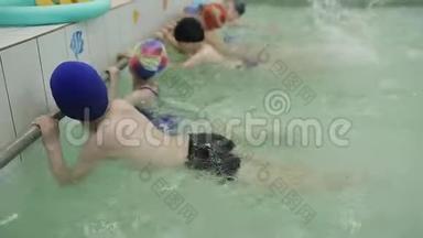 孩子们在游泳池里学习游泳。 孩子们在水中踢脚，造成水在水中的飞溅