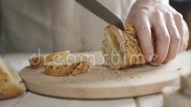 在桌上用<strong>黑芝麻</strong>切片面包。 巴盖特传统法国面包在桌子上切割特写。