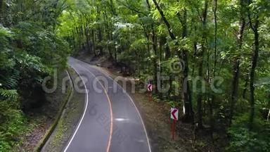 摩托车或摩托车在茂密的丛林中行驶狭窄的沥青路。 菲律宾博霍人工森林