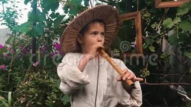 可爱有趣的小男孩穿着棉质的乡村服装和草帽在木制的锡纸上玩耍。 试图吹笛子的男孩子