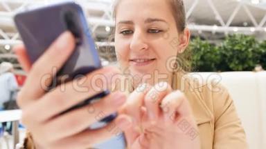 特写4k视频，微笑的年轻女子在智能手机上社交媒体上打字，同时坐在餐厅