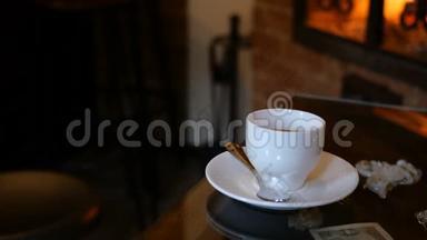 咖啡杯放在有壁炉的咖啡厅或<strong>餐厅</strong>的桌子上。 桌上闪着火焰. 浪漫的<strong>环境</strong>