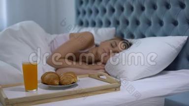 女孩睡在酒店房间，在靠近床的托盘上准备早餐，五星级服务