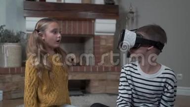 漂亮的白人女孩在一个戴着VR眼镜的<strong>小</strong>男孩面前挥手。 哥哥和<strong>姐姐</strong>在玩新设备