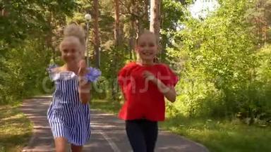 快乐少女少年在夏日公园的小路上奔跑.. 微笑的女朋友在人行道上奔跑，在镜头前跳跃