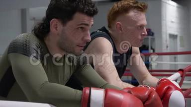 两名拳击手戴着拳击手套，在拳击俱乐部训练后休息。 疲惫的拳击手在拳击后放松
