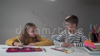 两个白人学童缓慢地翻动笔记本，微笑。 放学后男孩和女孩都很高兴