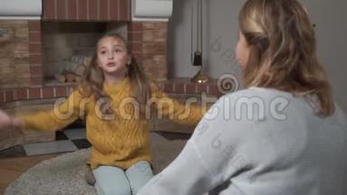 漂亮的白种人小女孩在家里坐在柔软的地毯上，有感情地说话和<strong>打手</strong>势。 她母亲