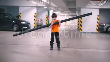 这个男孩帮助爸爸，在<strong>地下车库</strong>里用手拿着一根长管子。