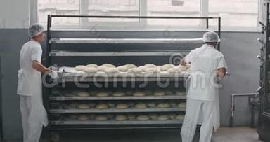 在一个大的面包店里，一个主要的面包师在一个工业烤箱机器的架子<strong>上走来走去</strong>